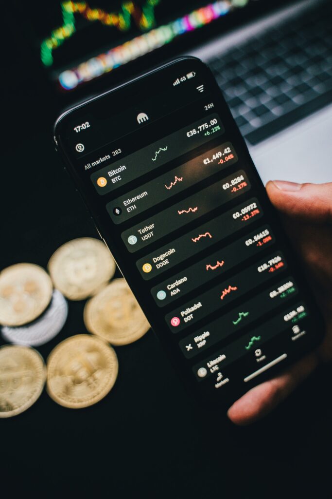 Close-up of a smartphone showing cryptocurrency trends with coins in the background.